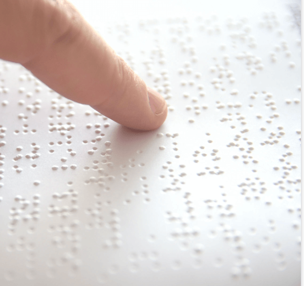 Dedo indicativo a ler uma folha impressa em braille